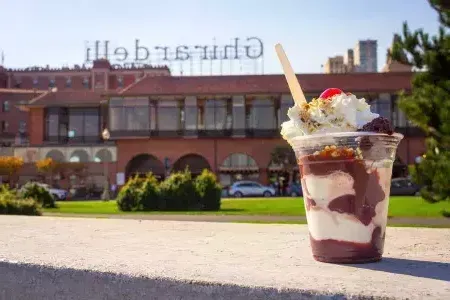 A chocolate sundae sits in the foreground with 吉尔德利广场 in the background.