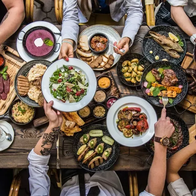 Pessoas sentadas à mesa de jantar, compartilhando comida.